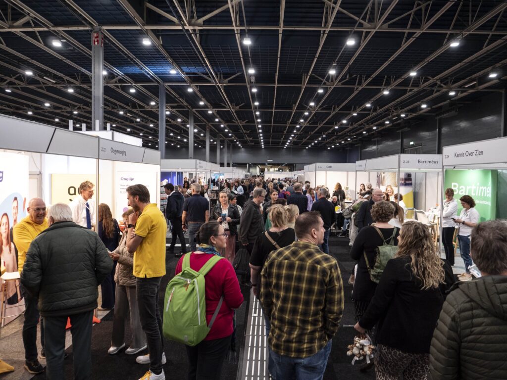 een gangpad vol bezoekers verkent de stands op een beurs