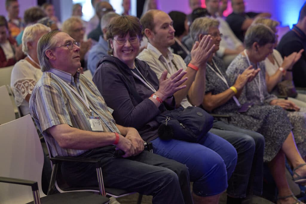 een man luistert aandachtig naar een workshop terwijl de vrouw naast hem applauduseert