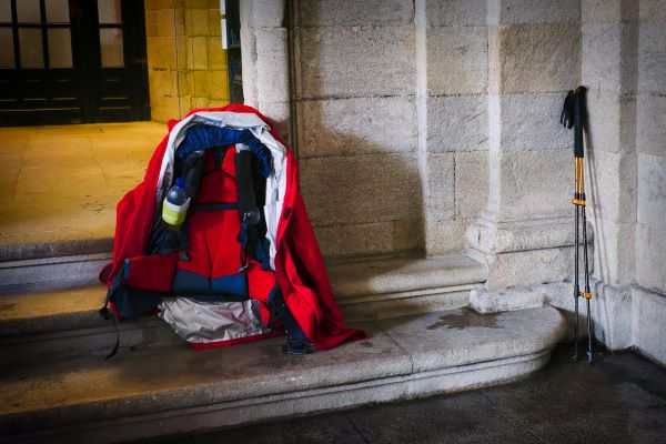 Een trekkersrugzak en wandelstokken op de stoep van een oud gebouw