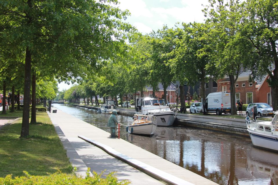 overzichtsfoto van de gracht in stadskanaal, er drijven bootjes langs de kade en er staan bomene in een groenstrook