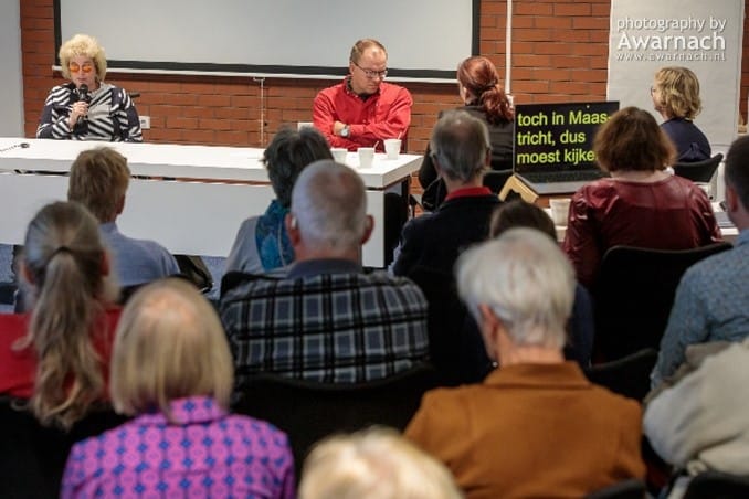 overzichtsfoto van een zaal vol aandachtige luisteraars