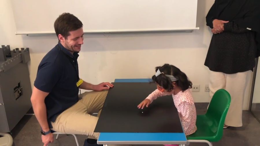 Een meisje ziet en pakt een klein object dat de onderzoeker voor haar op tafel heeft gelegd